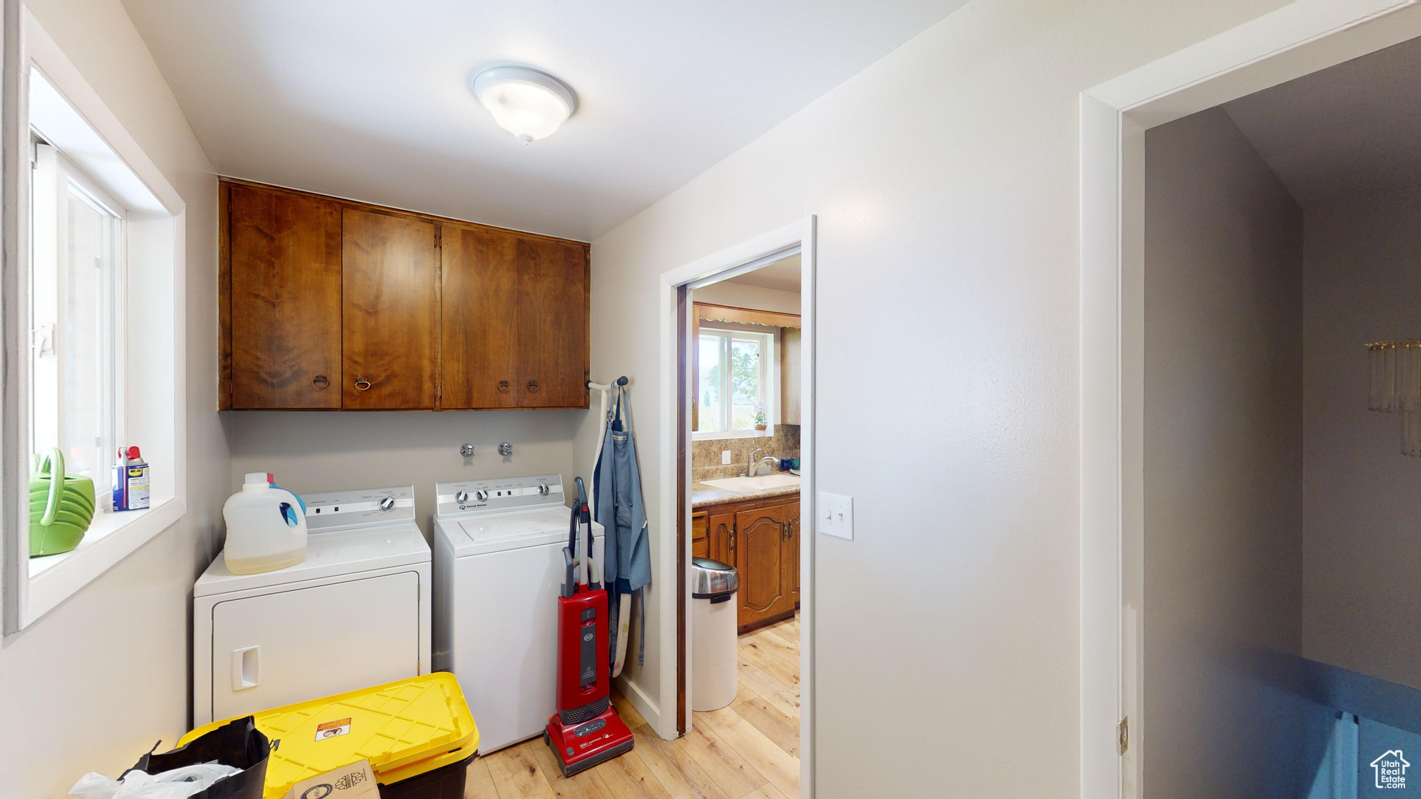 Laundry area with sink, cabinets, light wood-type flooring, and independent washer and dryer