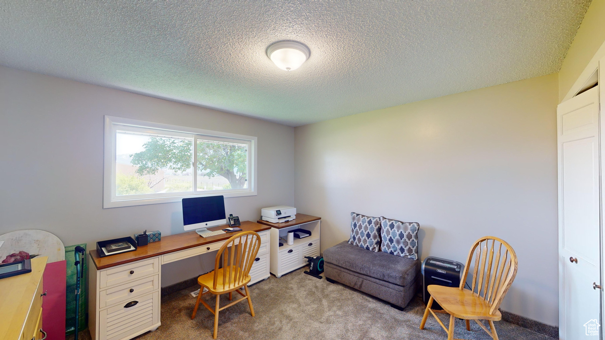 Office space featuring a textured ceiling and light colored carpet