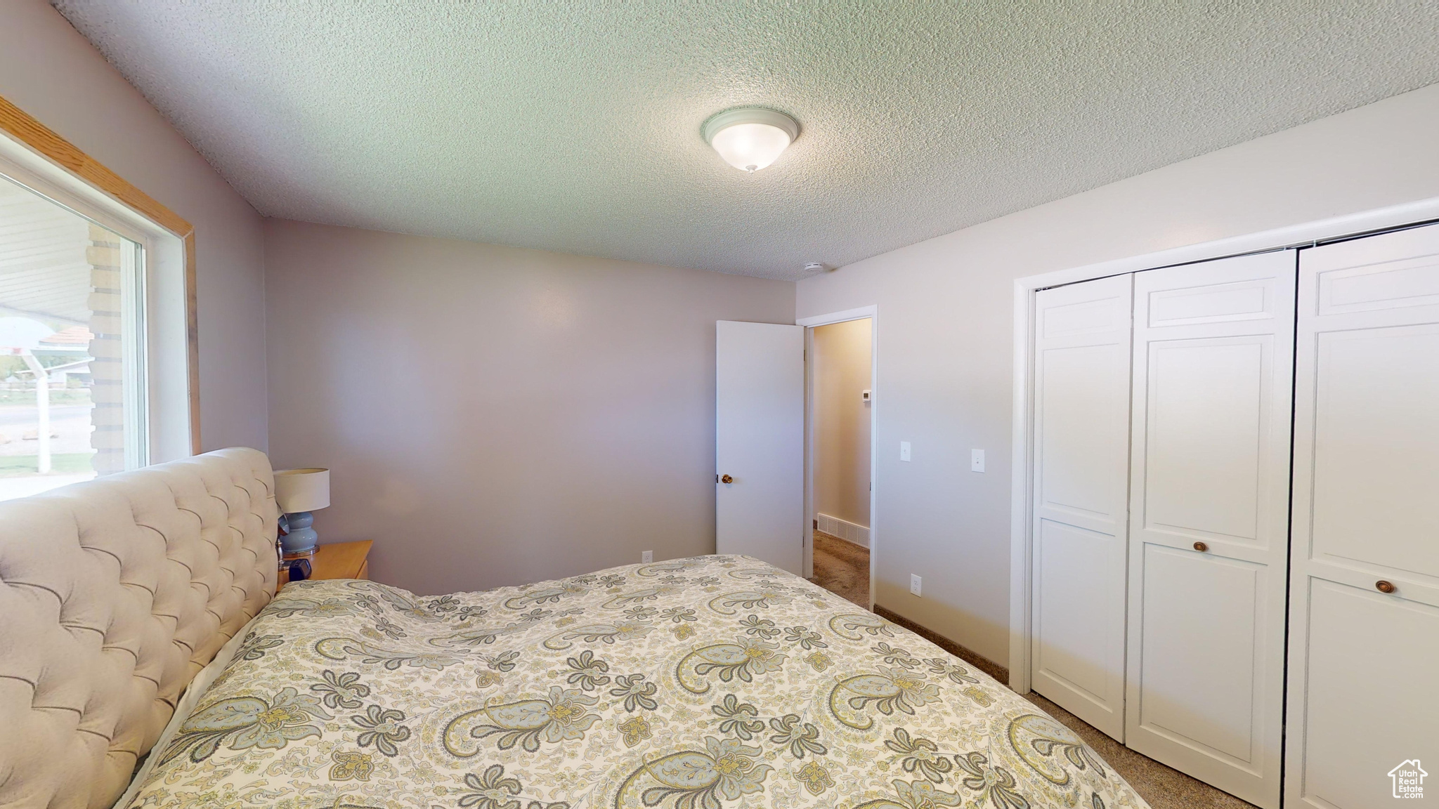 Bedroom with a textured ceiling, a closet, and carpet floors