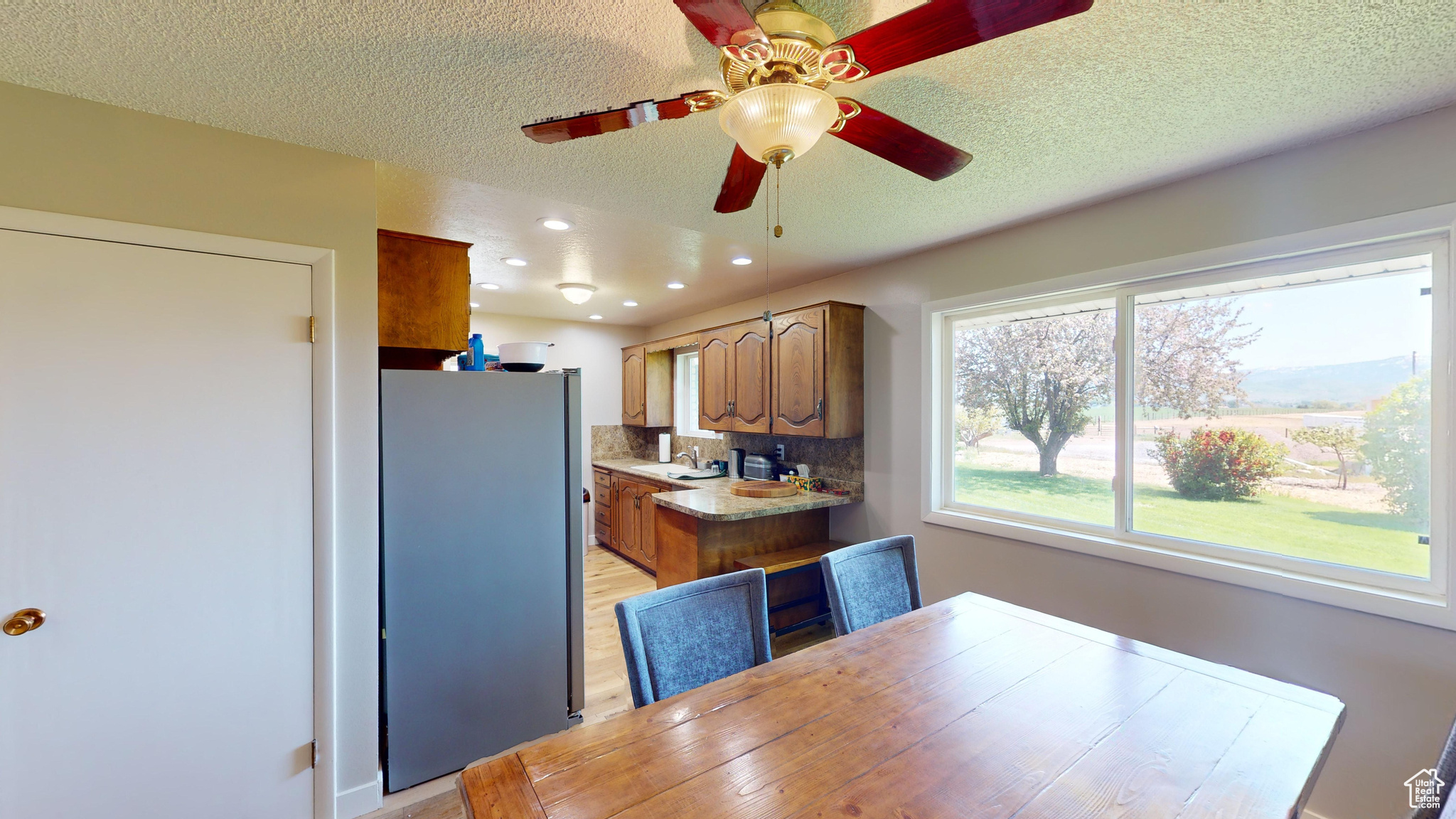 Dining area with ceiling fan, a textured ceiling, light wood-type flooring, and sink