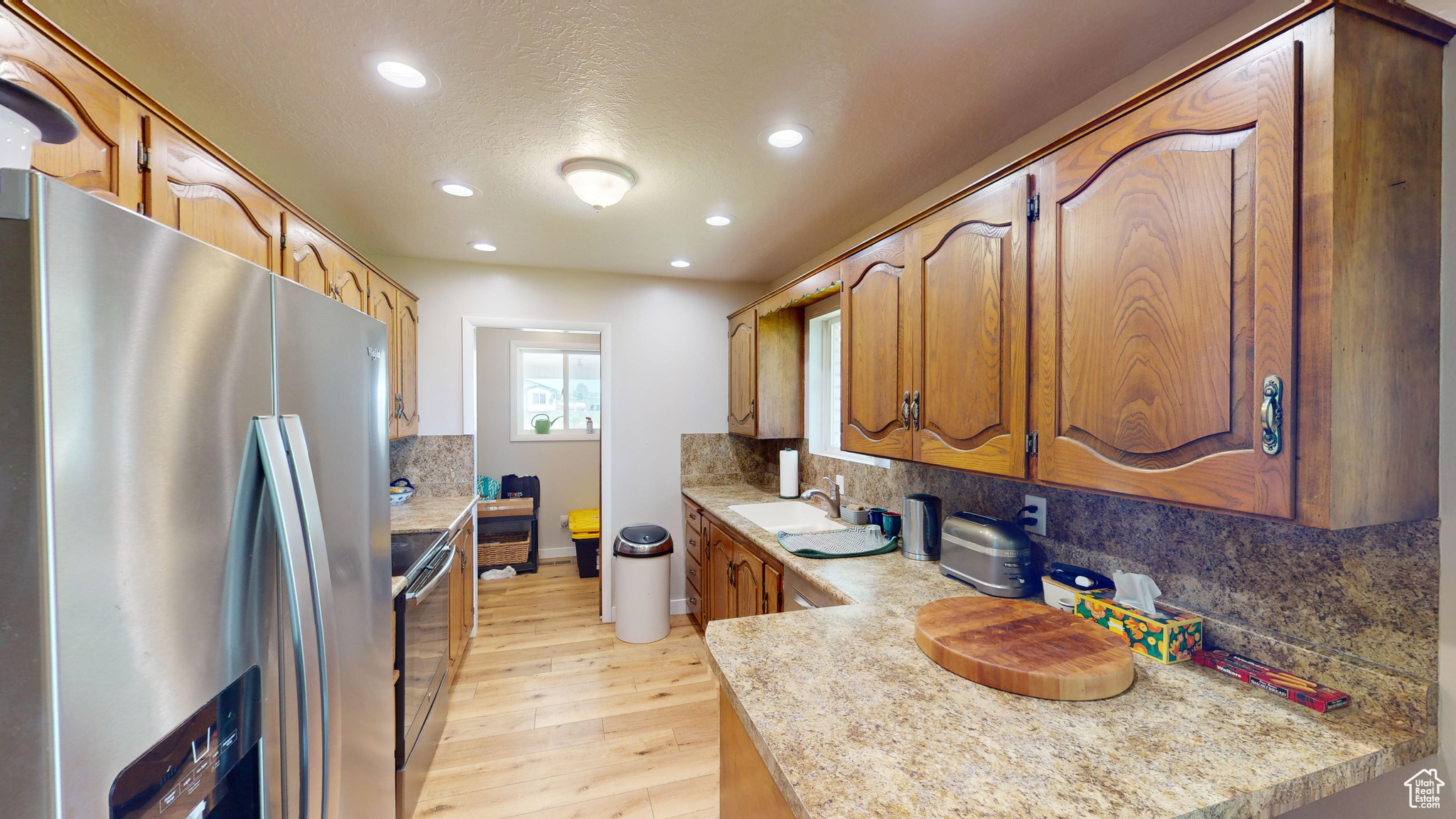 Kitchen featuring sink, light hardwood / wood-style floors, tasteful backsplash, and appliances with stainless steel finishes