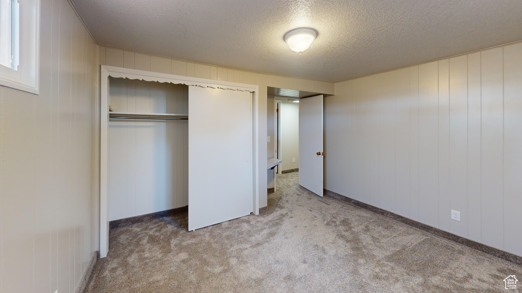 Unfurnished bedroom featuring a closet, a textured ceiling, and carpet floors