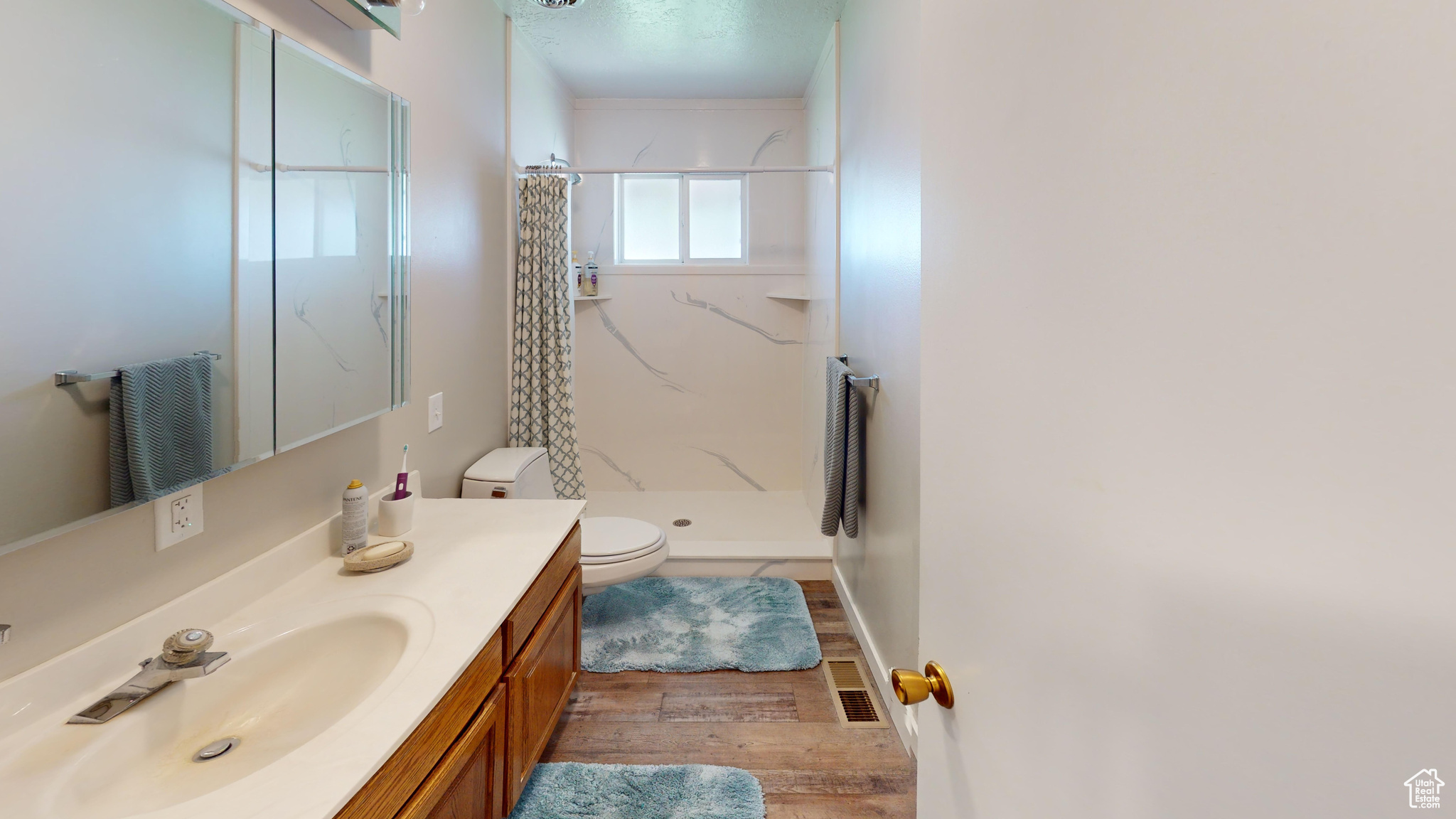 Bathroom with a shower with shower curtain, wood-type flooring, toilet, and large vanity