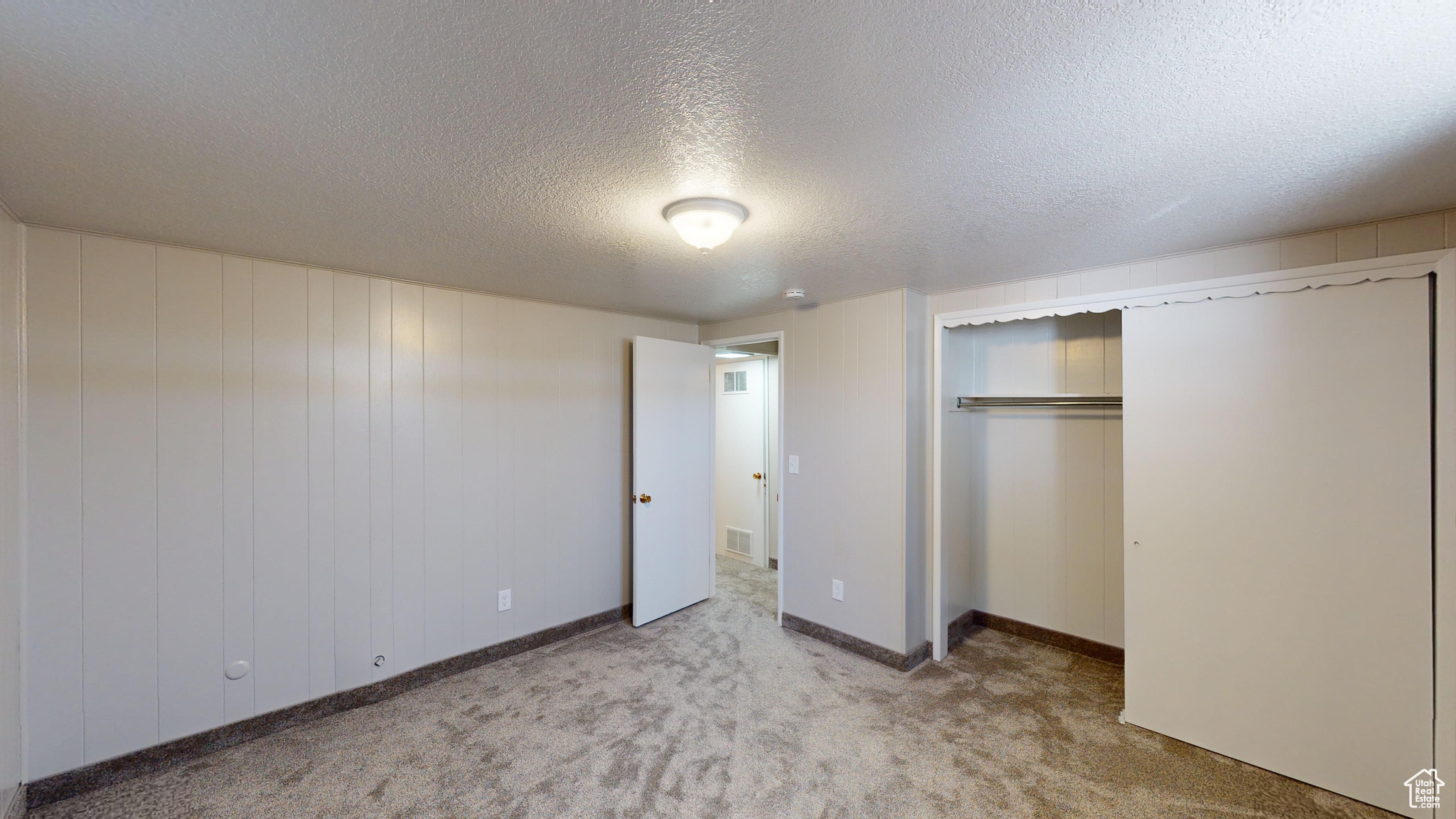 Unfurnished bedroom with a closet, a textured ceiling, and light carpet