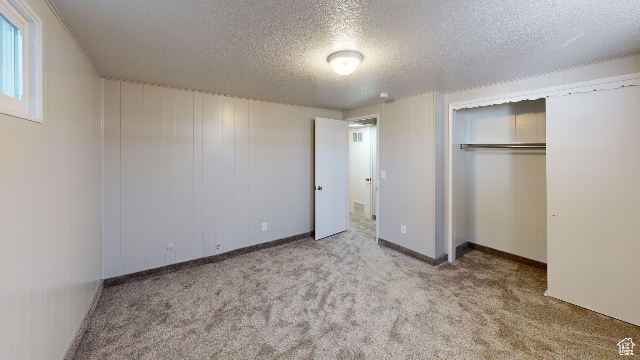 Unfurnished bedroom with a textured ceiling, a closet, and light colored carpet