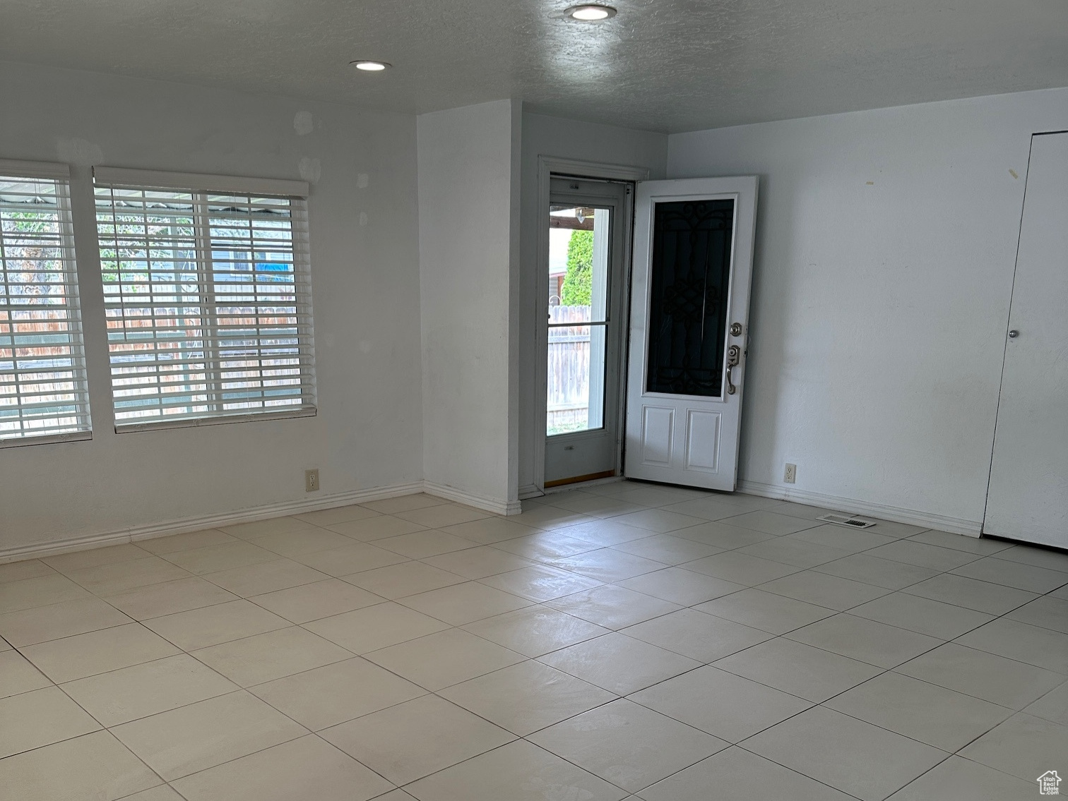 Unfurnished room with a textured ceiling and light tile floors