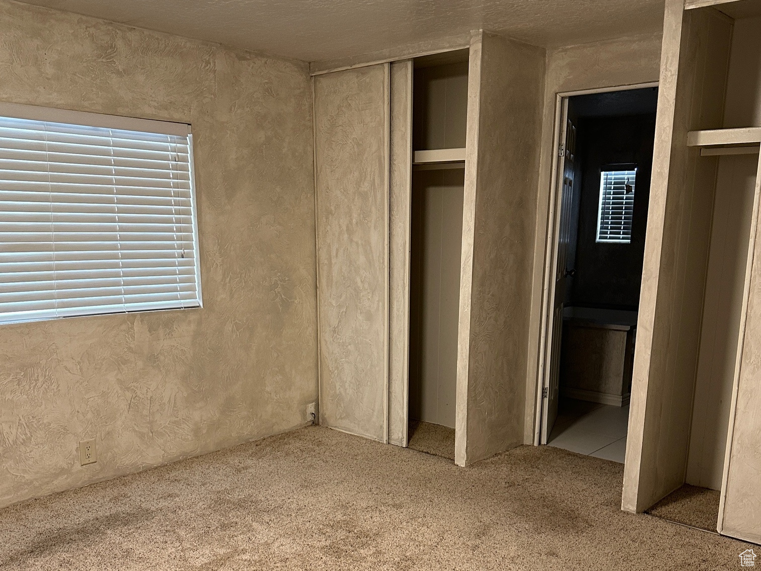 Unfurnished bedroom with carpet floors, a textured ceiling, and ensuite bath