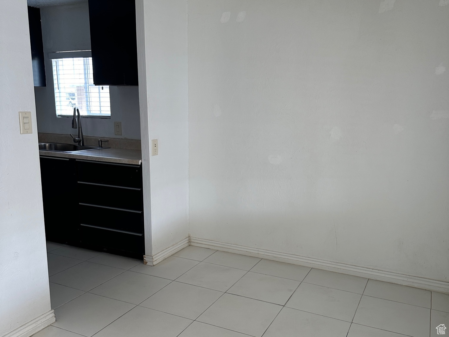 Empty room with sink, a textured ceiling, and light tile floors