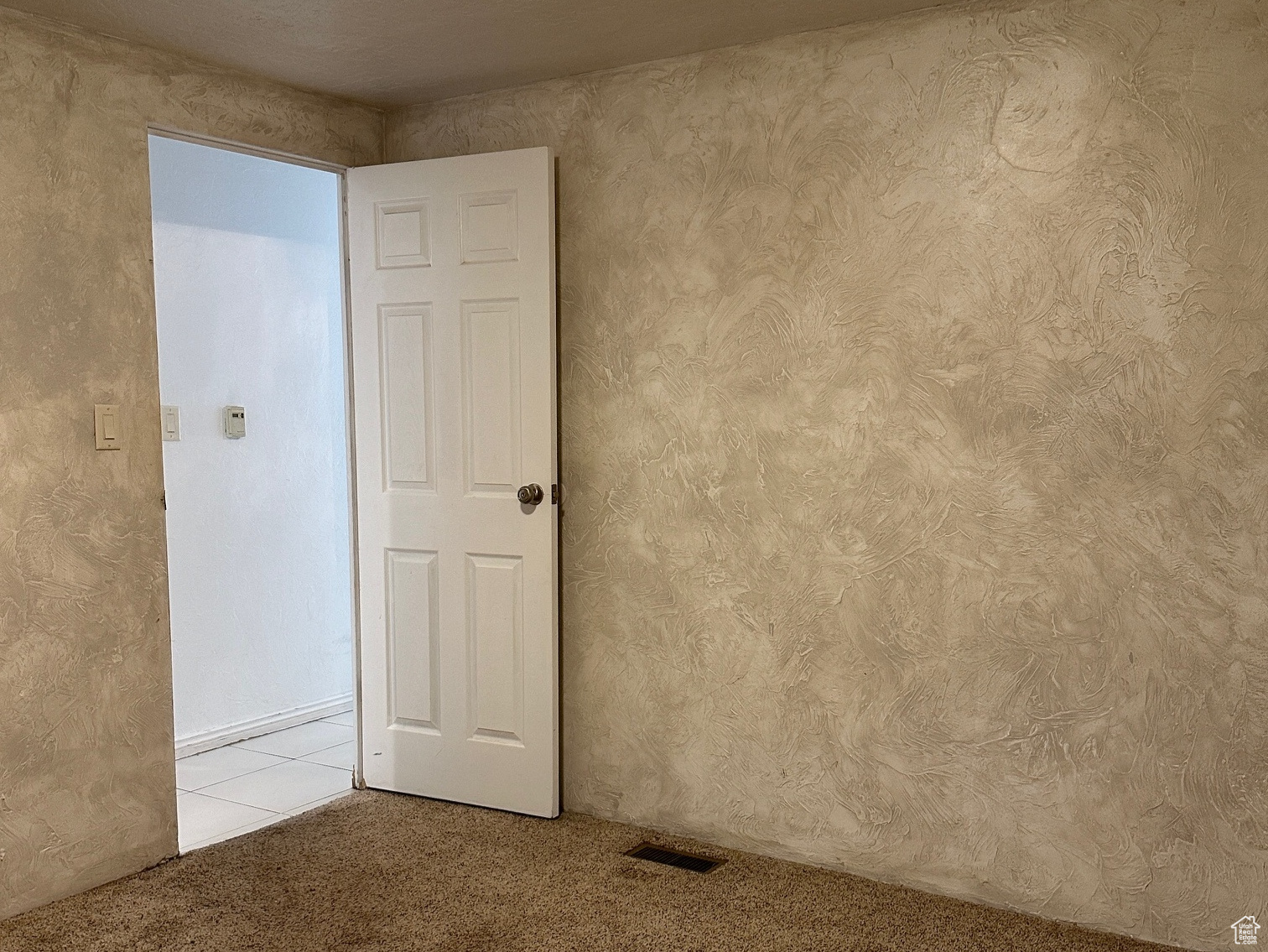 Spare room featuring a textured ceiling and light colored carpet