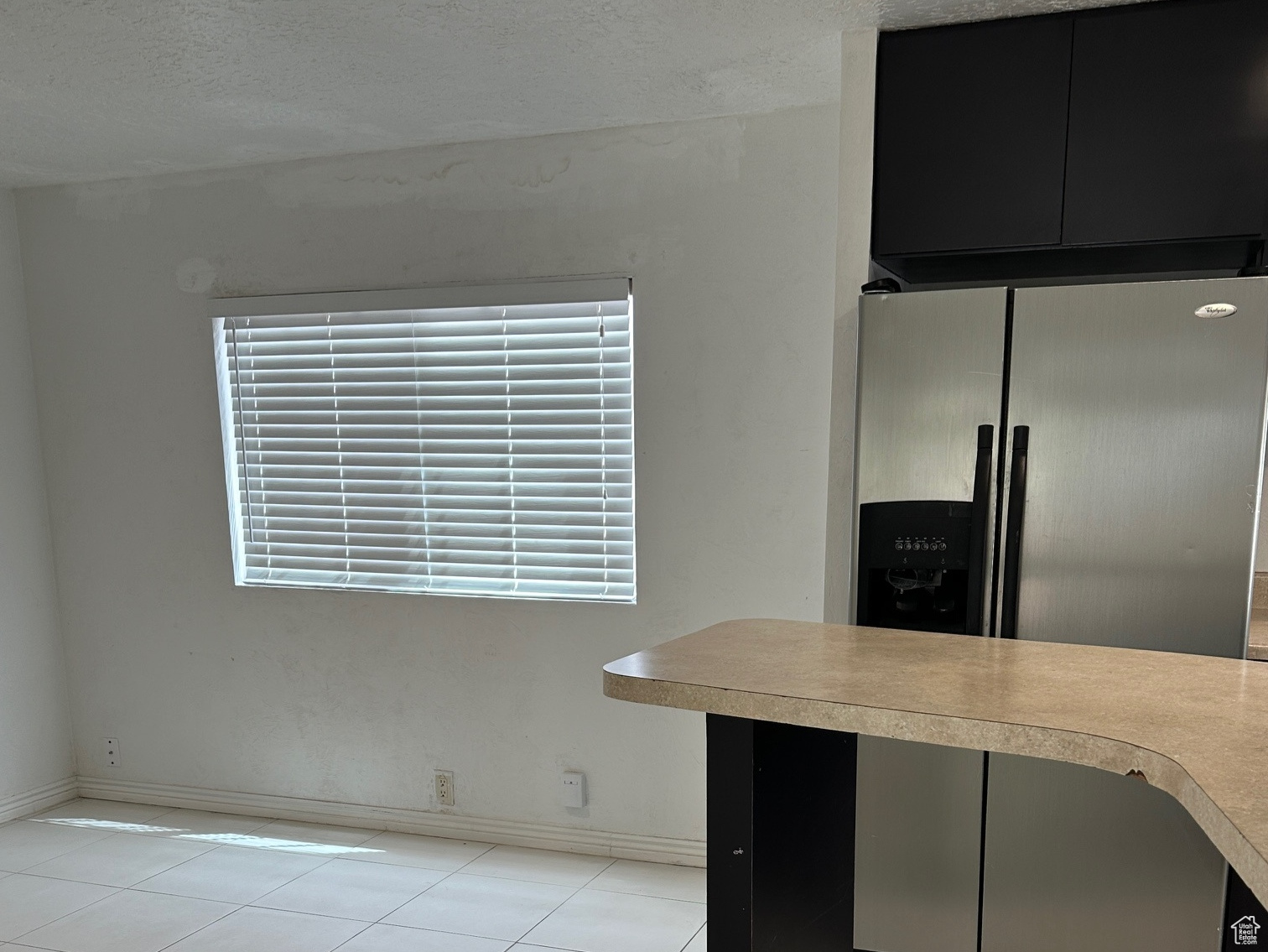 Kitchen with a textured ceiling and light tile floors