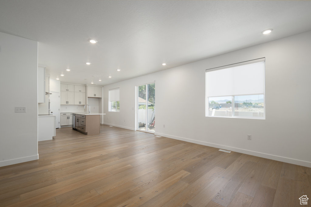 Unfurnished living room featuring light hardwood / wood-style floors and sink