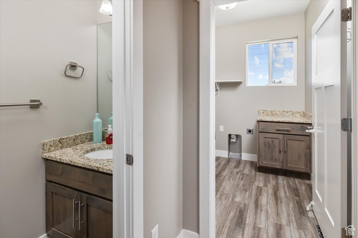 Bathroom with vanity with extensive cabinet space and hardwood / wood-style floors