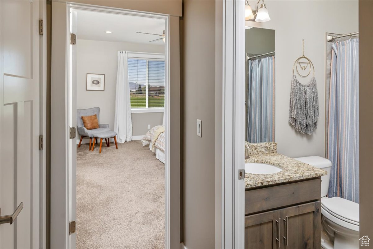 Bathroom featuring vanity with extensive cabinet space, ceiling fan, and toilet