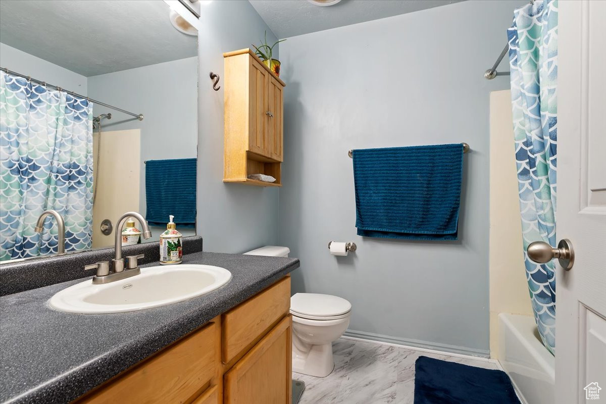 Full bathroom with tile floors, shower / tub combo, large vanity, and toilet