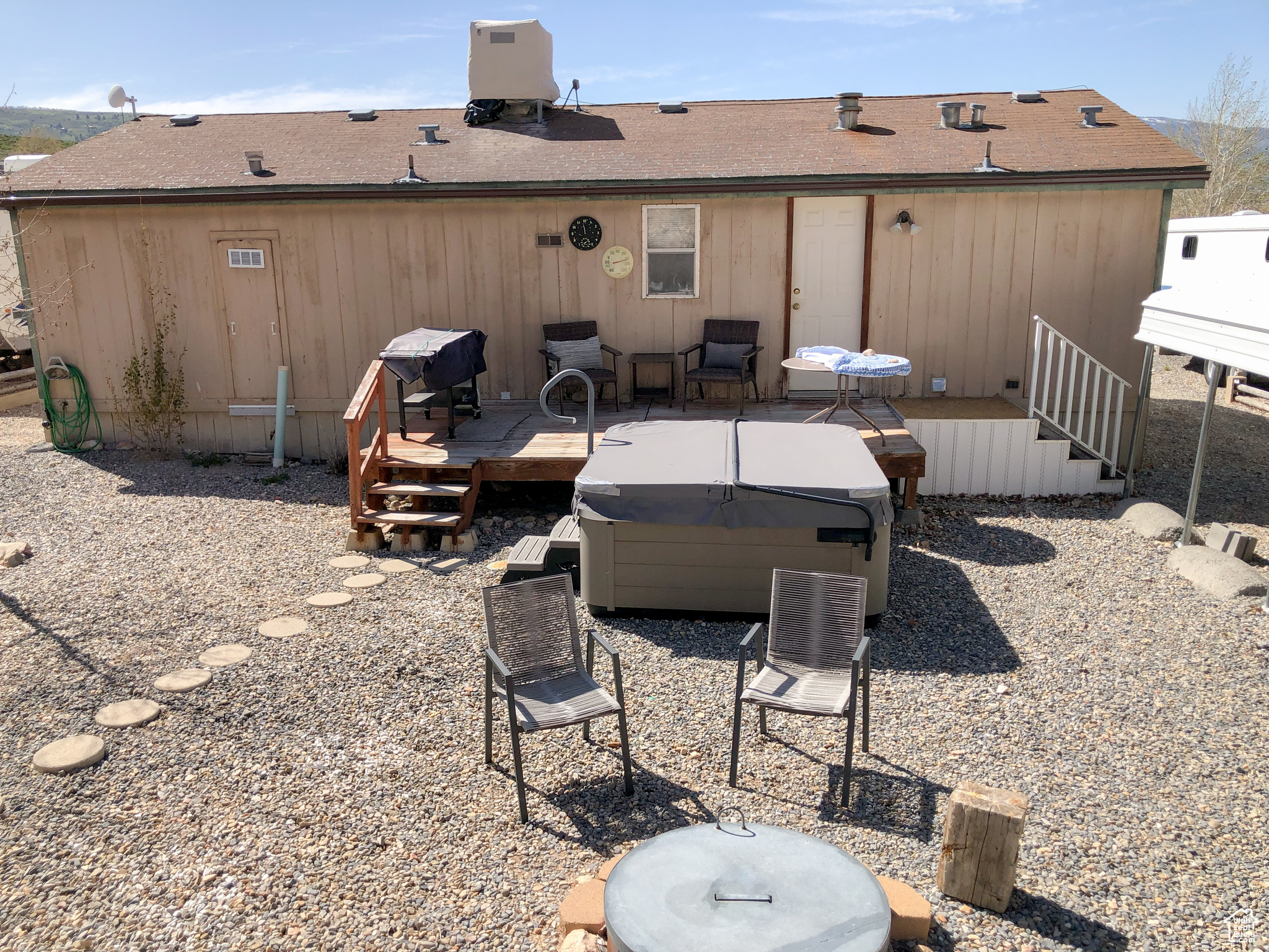 Back of property featuring a hot tub, fire pit, and a deck