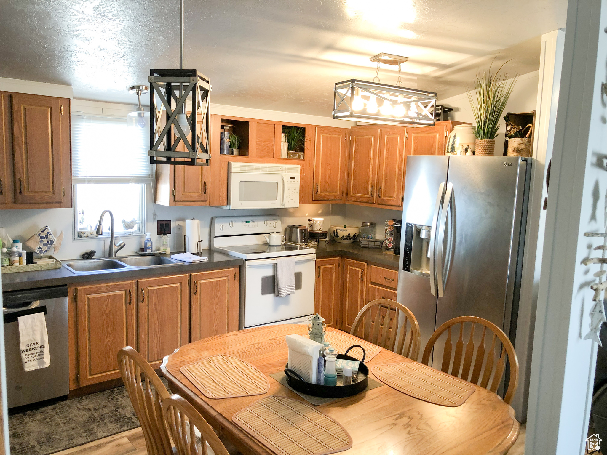 Kitchen with decorative light fixtures, sink, light wood-type flooring, and stainless steel appliances