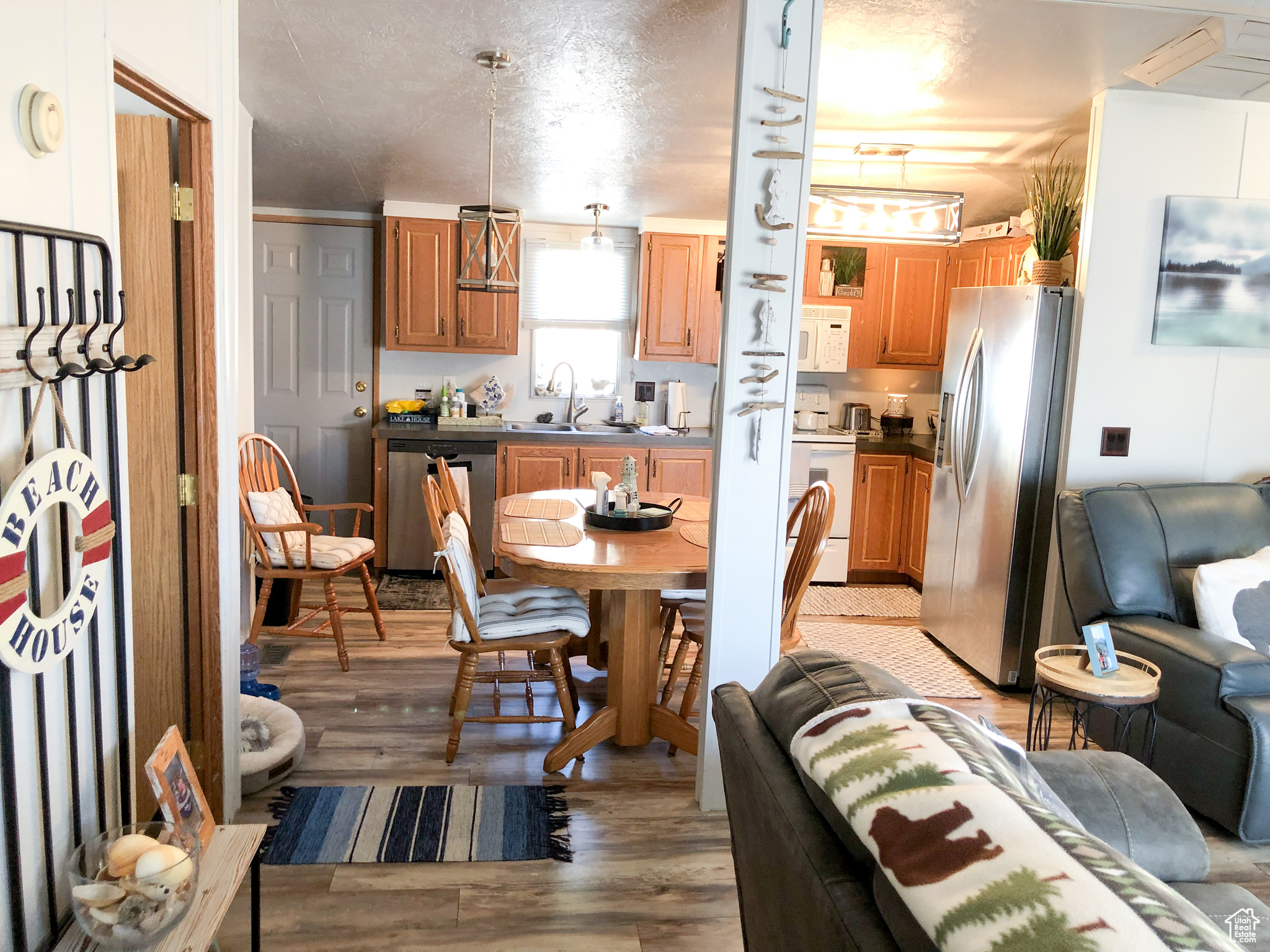 Interior space featuring decorative light fixtures, sink, light wood-type flooring, and stainless steel appliances