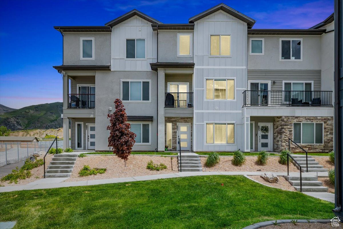 View of front of house with a lawn and a balcony