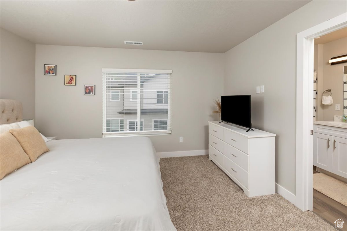 Carpeted bedroom featuring ensuite bath