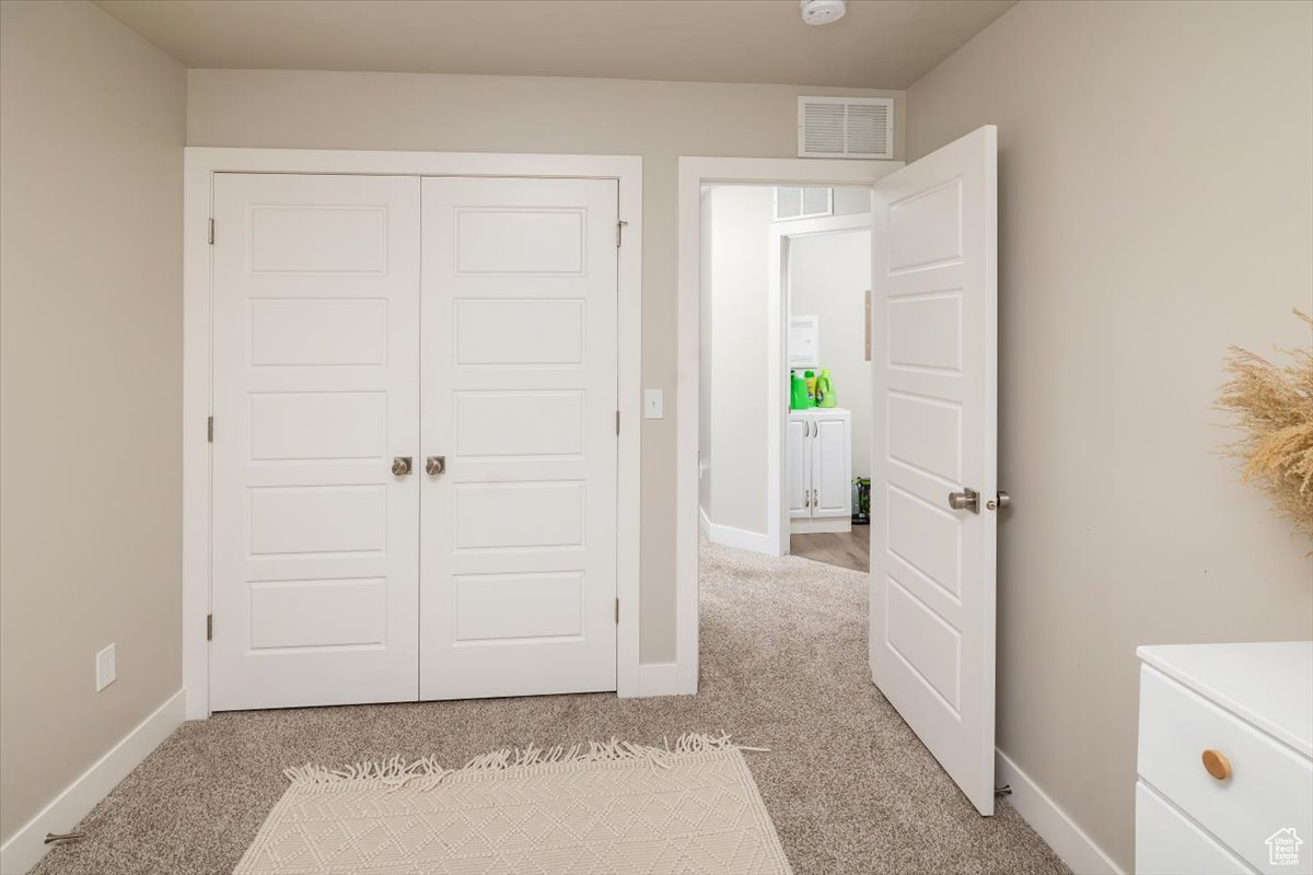 Unfurnished bedroom featuring light carpet and a closet