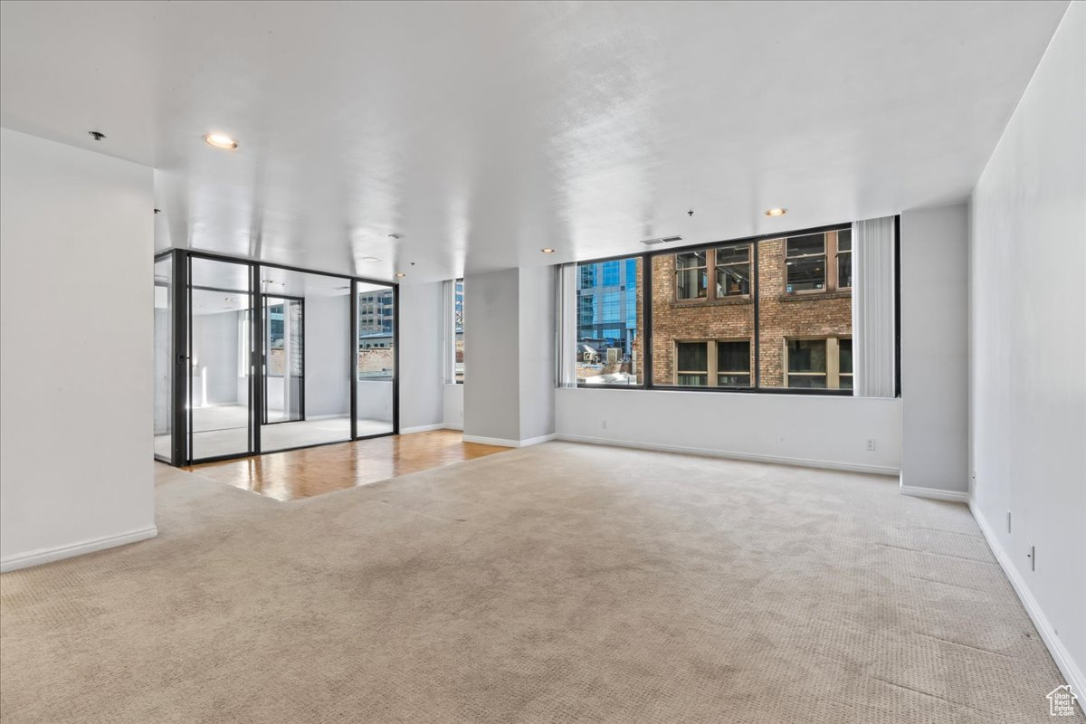 Unfurnished room featuring floor to ceiling windows and light colored carpet