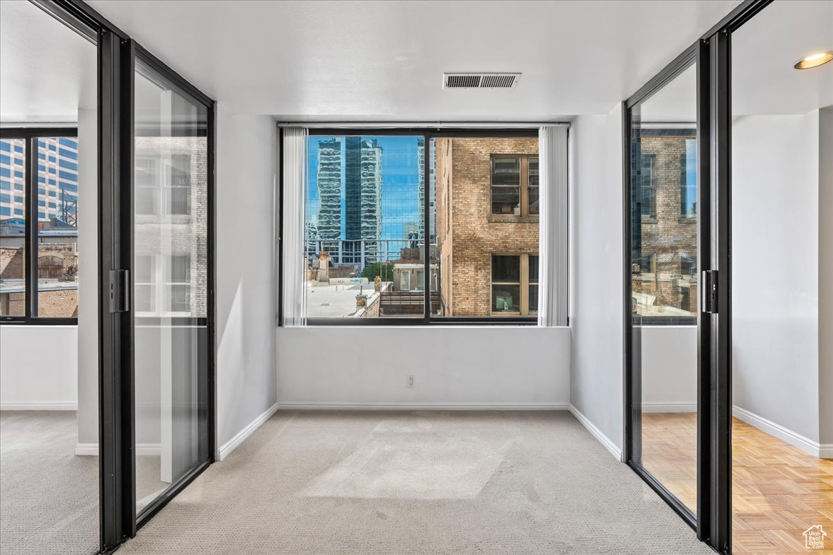 Unfurnished bedroom with light carpet and multiple windows