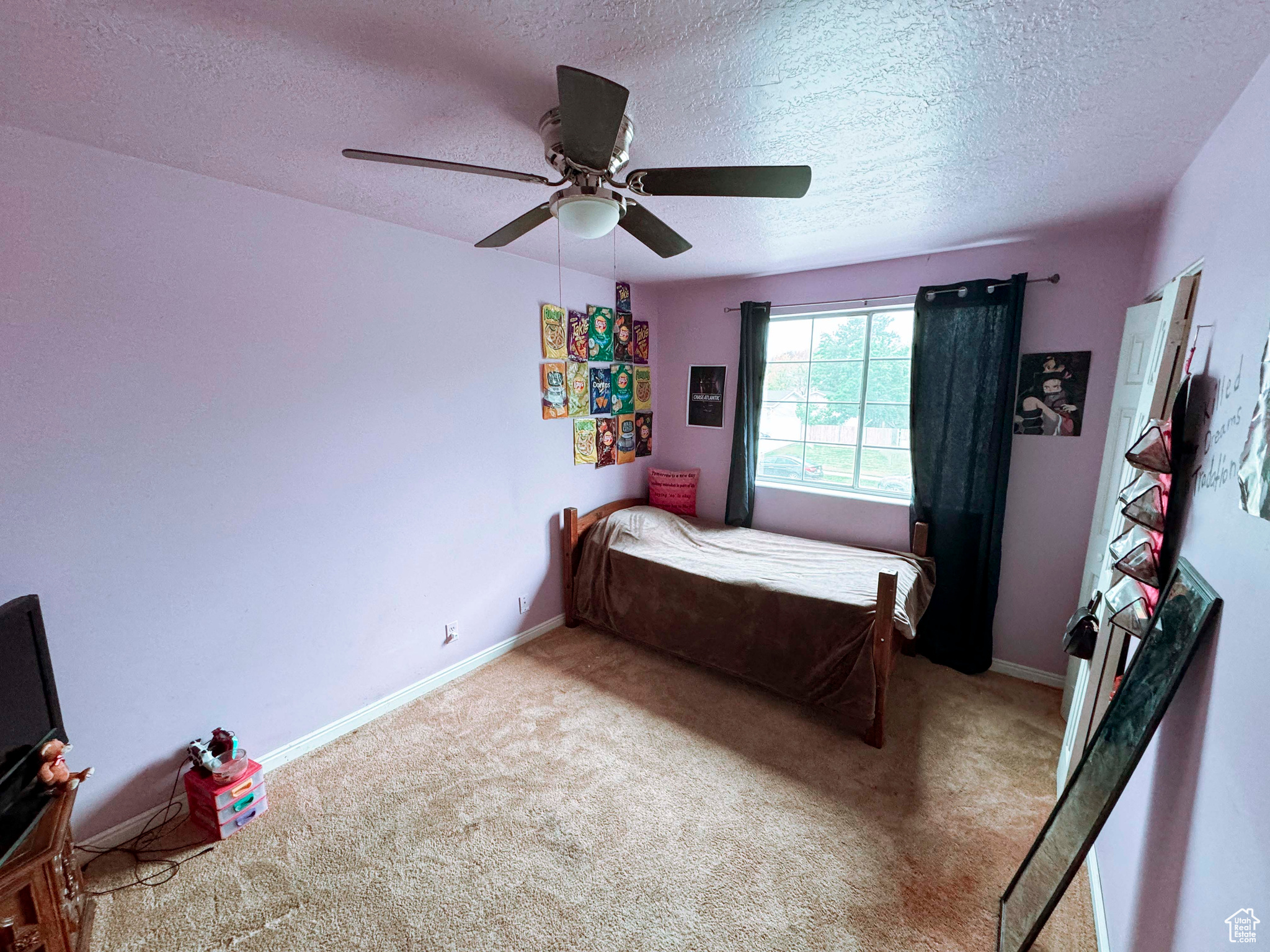 Carpeted bedroom featuring ceiling fan and a textured ceiling