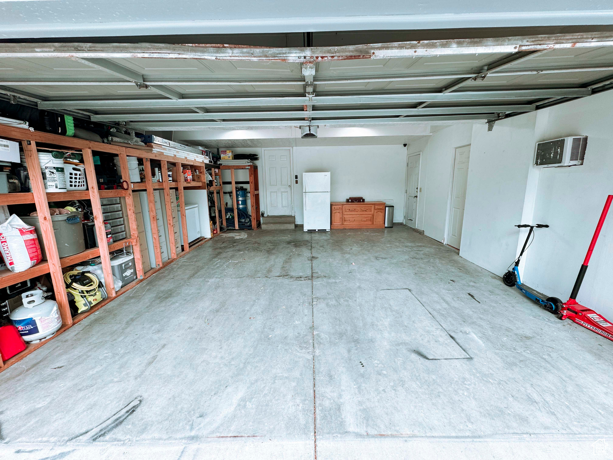 Garage with a wall unit AC and white fridge