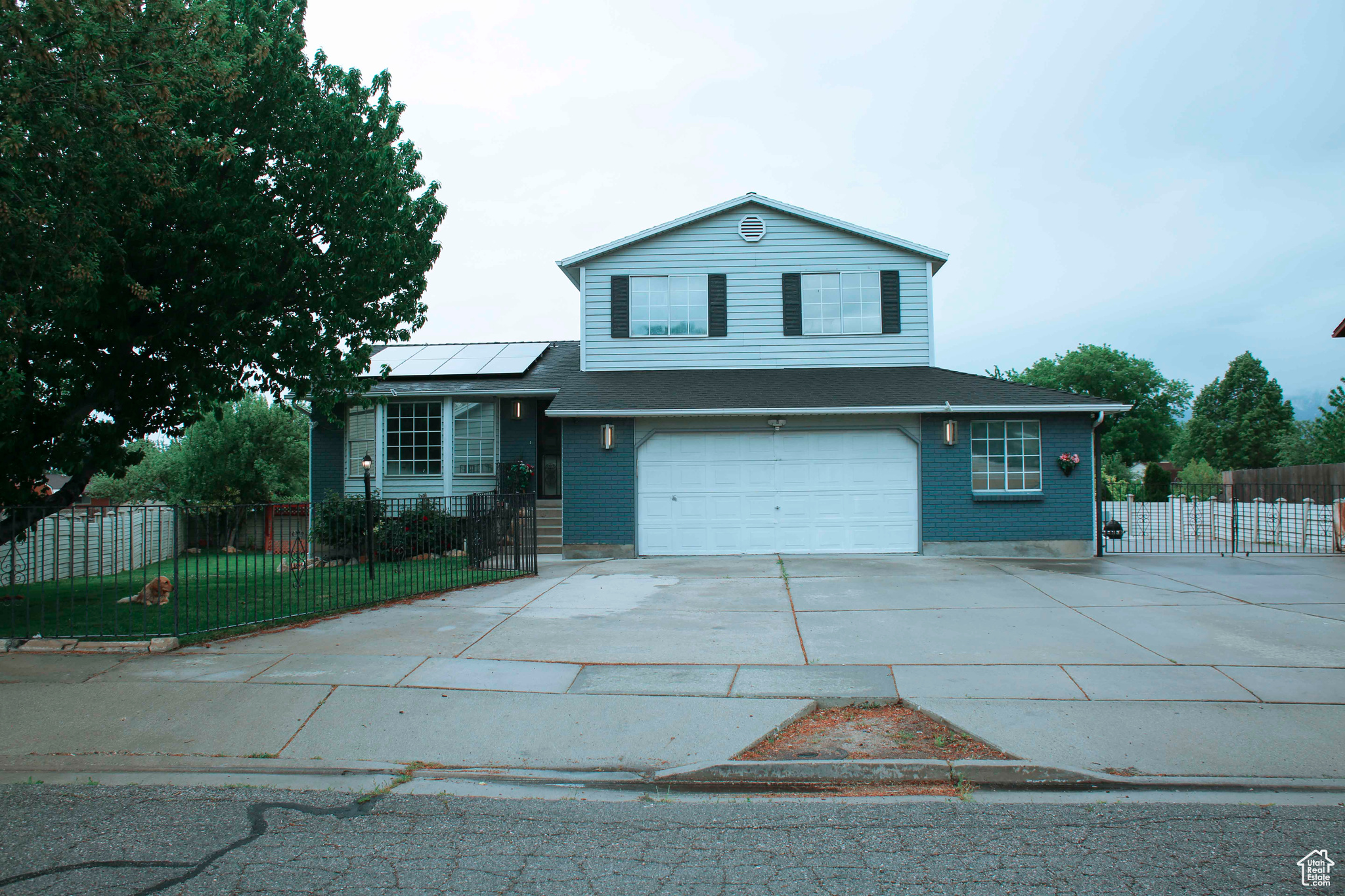 View of front facade featuring a garage and solar panels