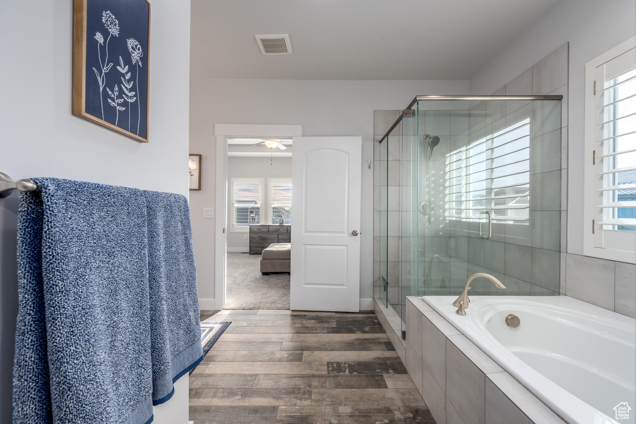 Bathroom with ceiling fan, hardwood / wood-style flooring, and separate shower and tub