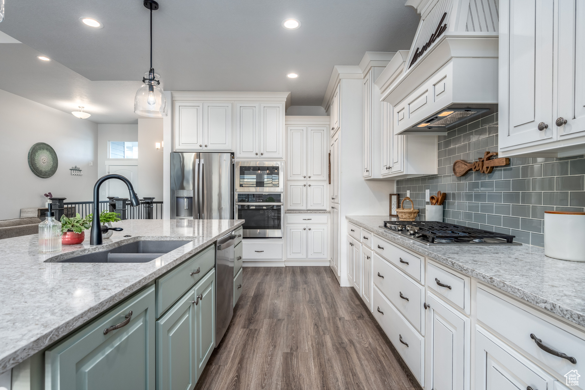 Kitchen with white cabinetry, dark hardwood / wood-style flooring, appliances with stainless steel finishes, backsplash, and pendant lighting