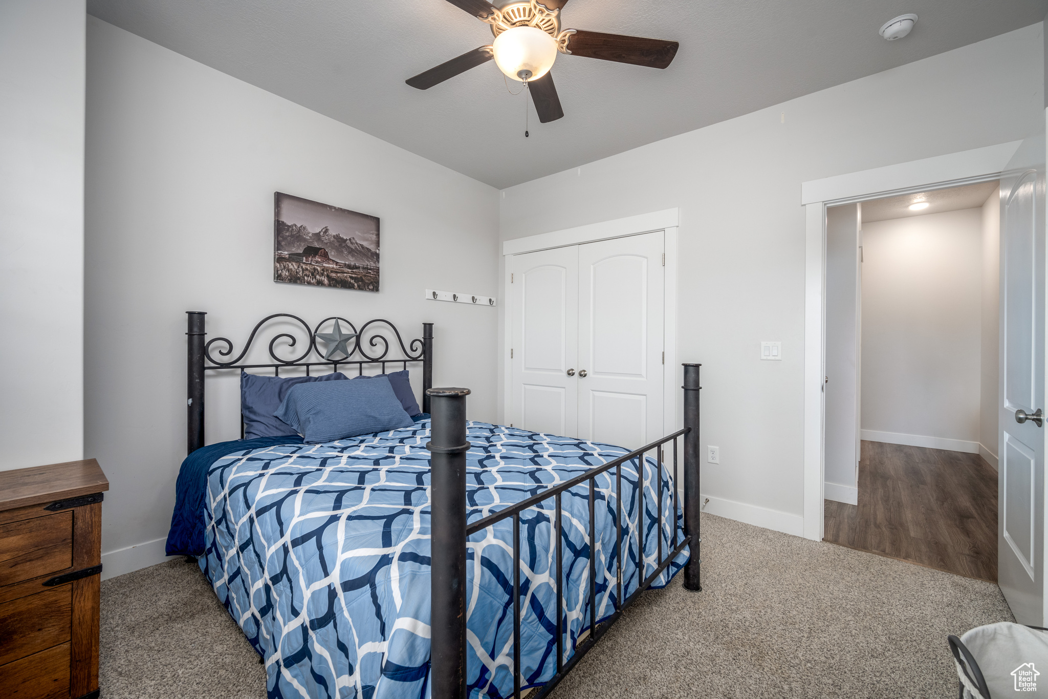 Carpeted bedroom with ceiling fan and a closet