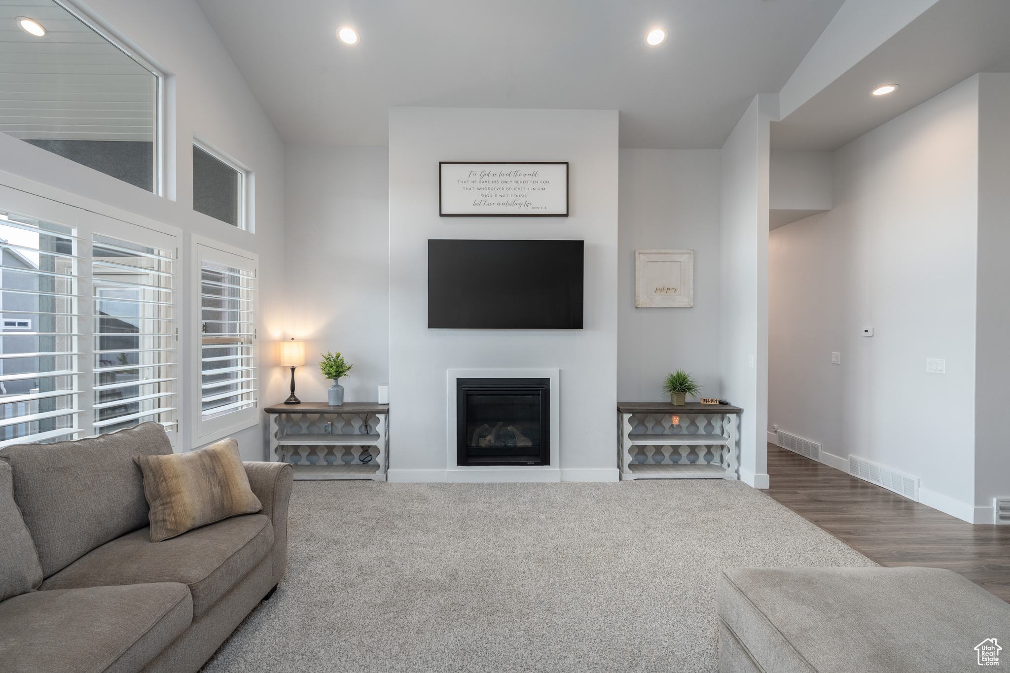 Carpeted living room featuring high vaulted ceiling and a healthy amount of sunlight