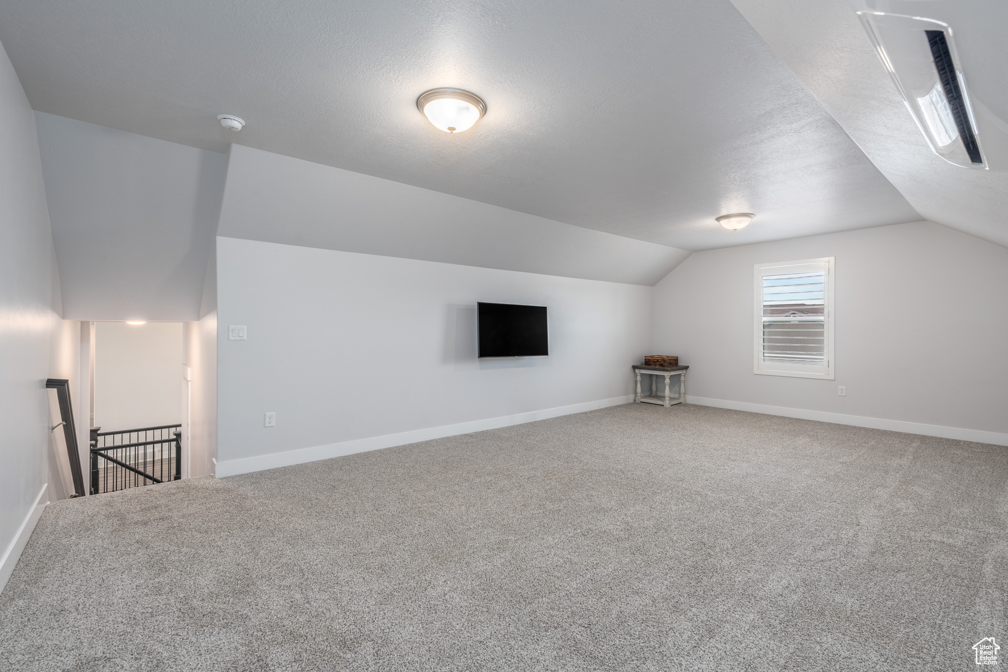 Bonus room with carpet flooring and vaulted ceiling