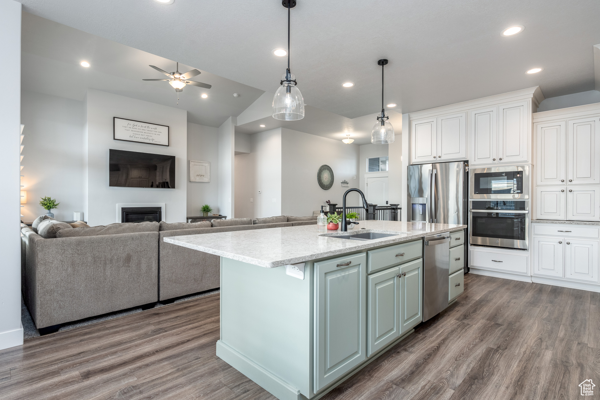 Kitchen with stainless steel appliances, wood-type flooring, sink, and a kitchen island with sink