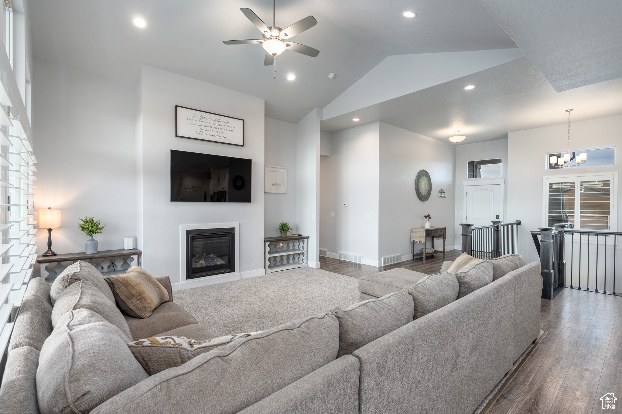 Living room with high vaulted ceiling, wood-type flooring, and ceiling fan with notable chandelier