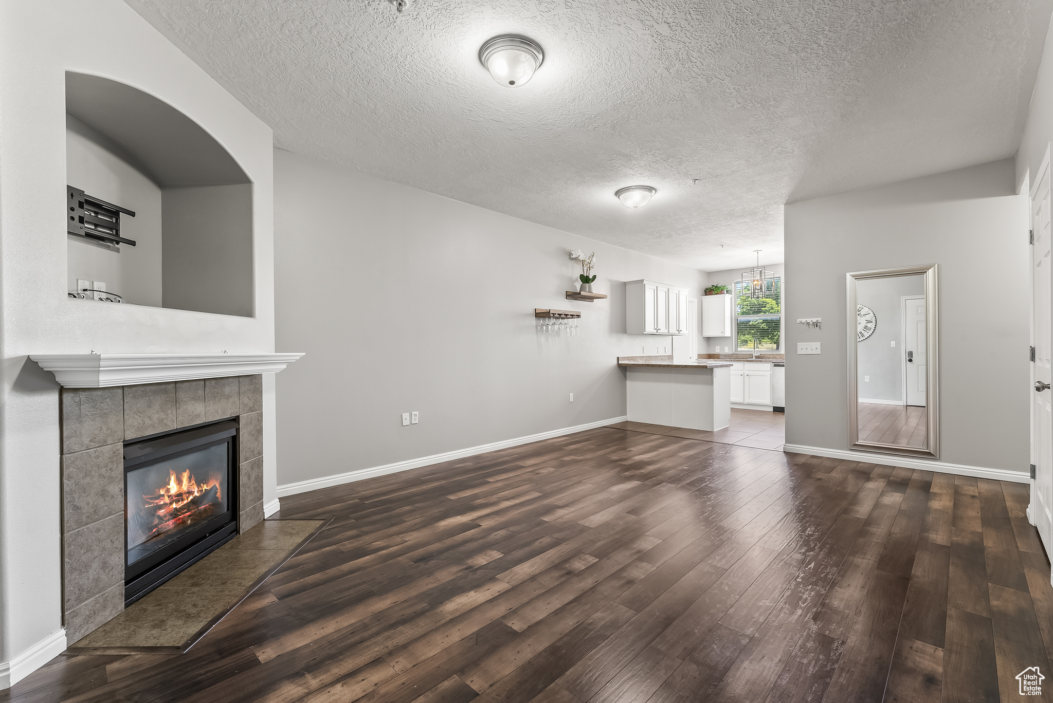 Unfurnished living room with dark hardwood / wood-style flooring, a tiled fireplace, and a textured ceiling