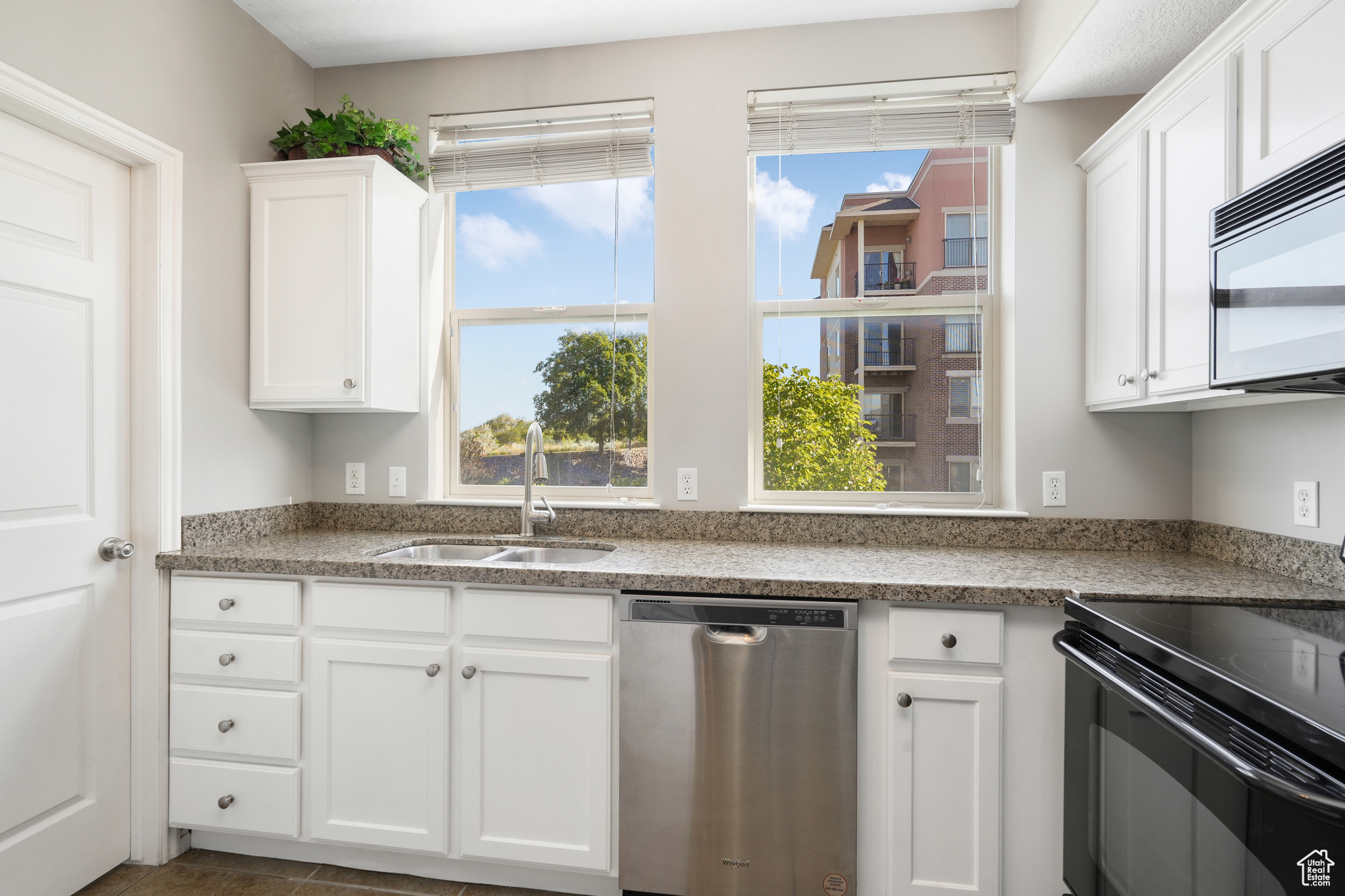 Kitchen with white cabinetry, black electric range oven, built in microwave, and stainless steel dishwasher