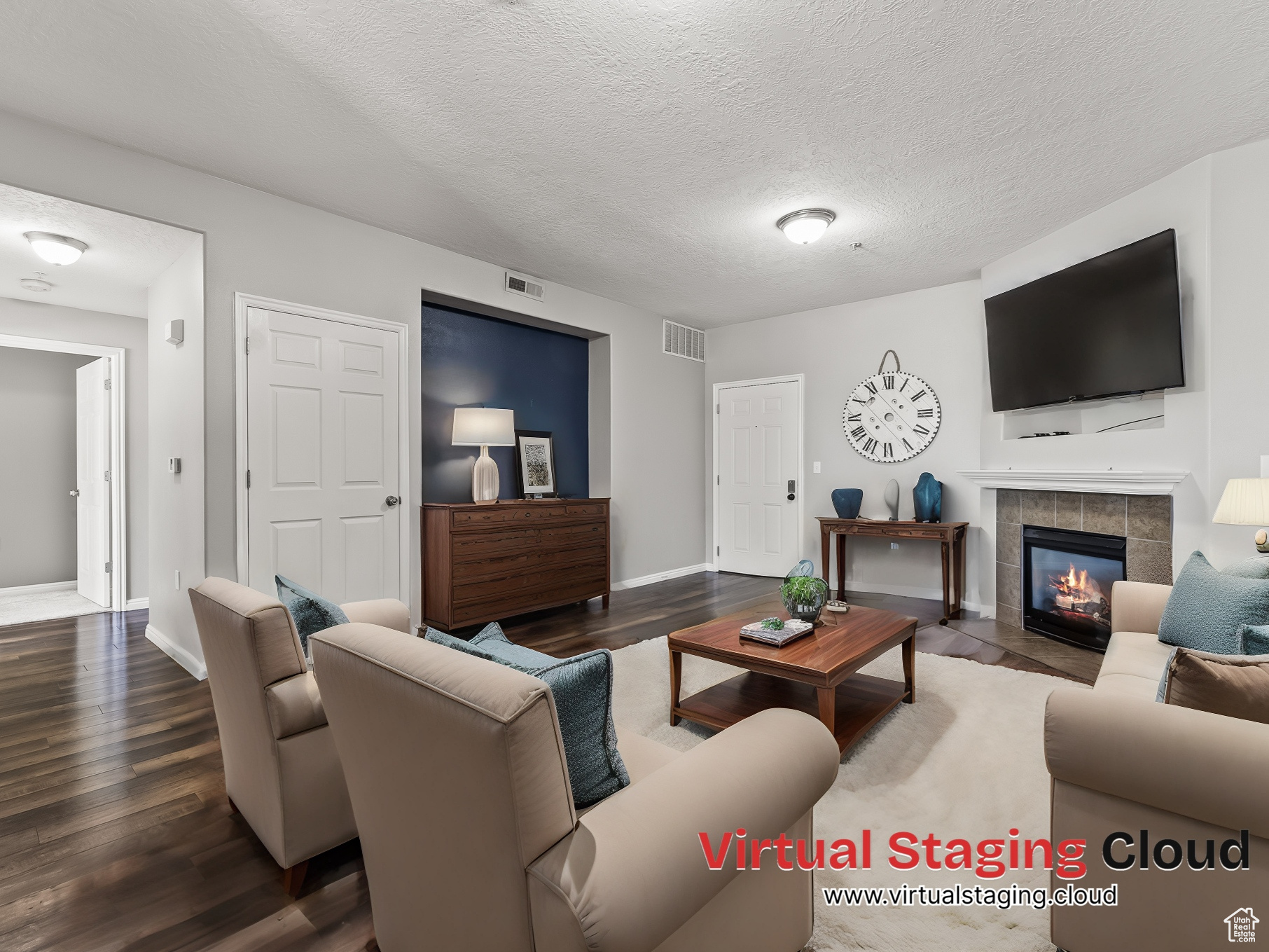 Living room featuring dark hardwood / wood-style flooring, a tiled fireplace, and a textured ceiling.