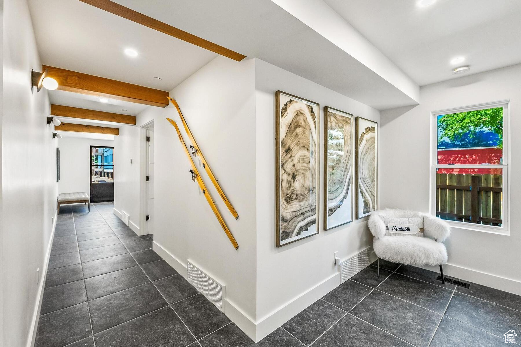 Hallway with beamed ceiling and dark tile floors