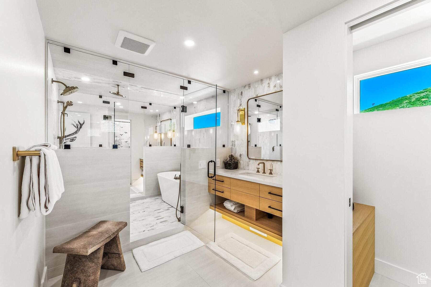 Bathroom featuring tile floors, plus walk in shower, vanity, and tile walls