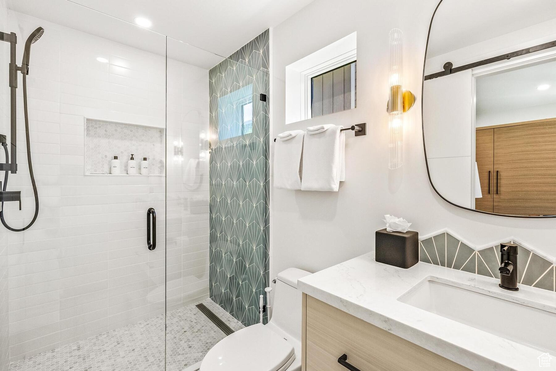 Bathroom featuring walk in shower, large vanity, and toilet