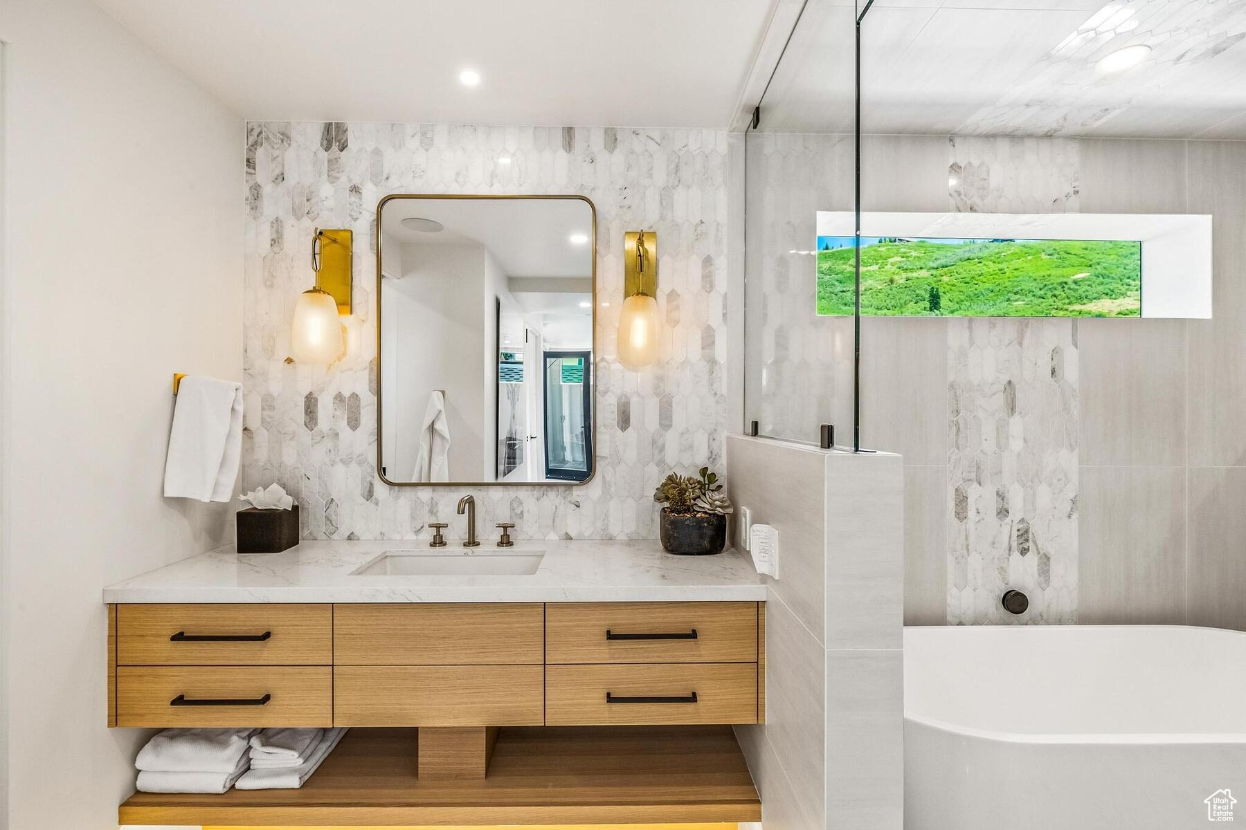 Bathroom with tile walls, vanity, and a bath to relax in