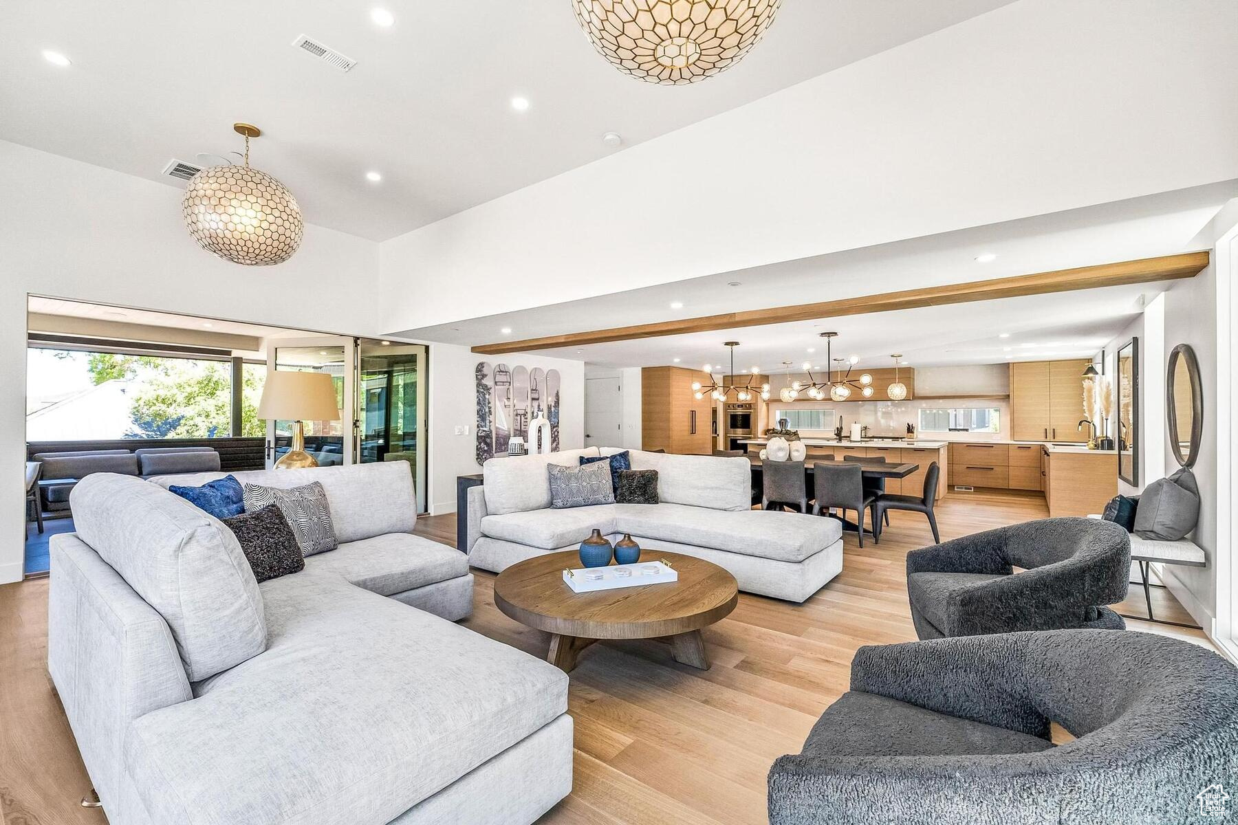 Living room featuring a towering ceiling, a chandelier, and light hardwood / wood-style flooring