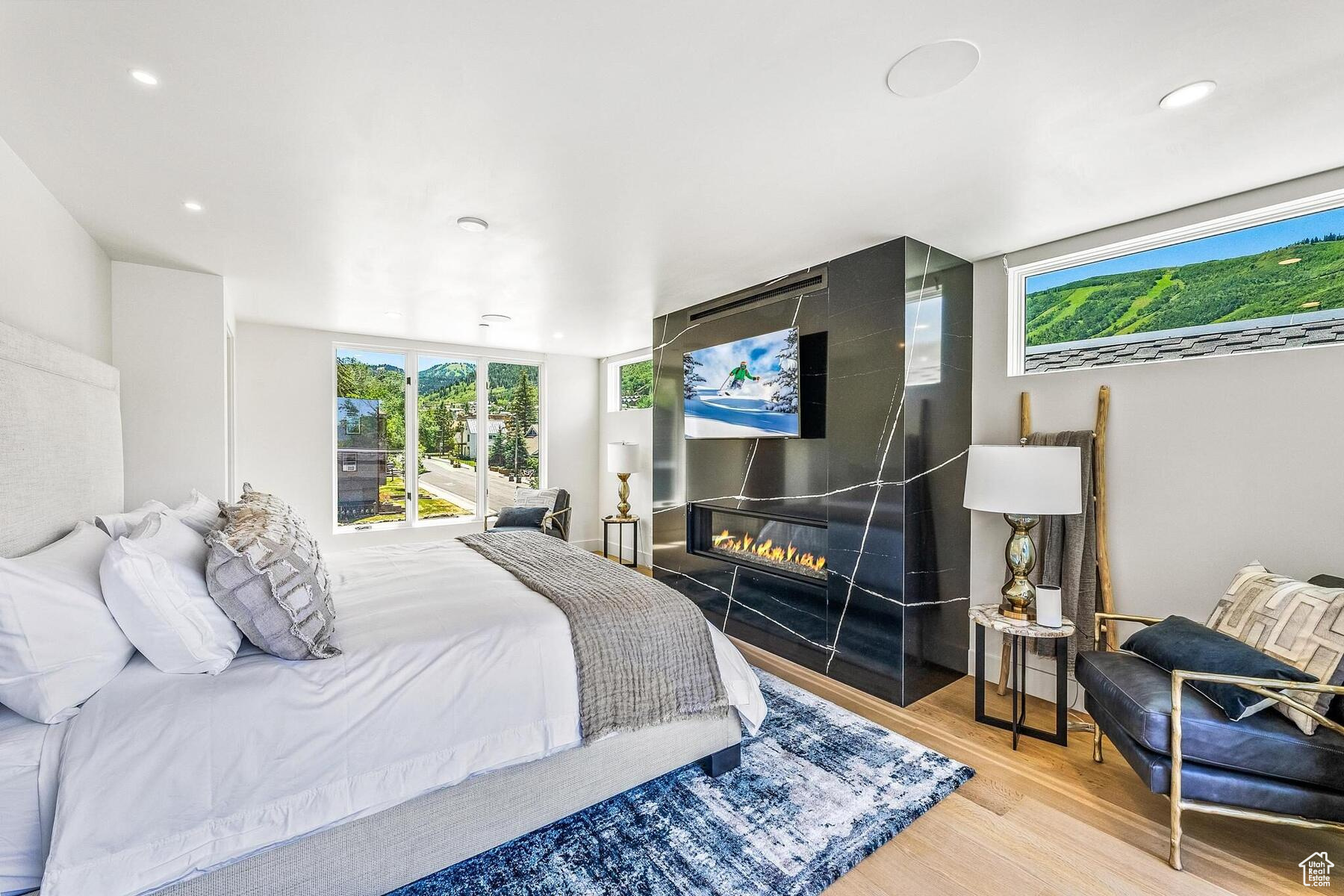 Bedroom with a large fireplace and light hardwood / wood-style flooring