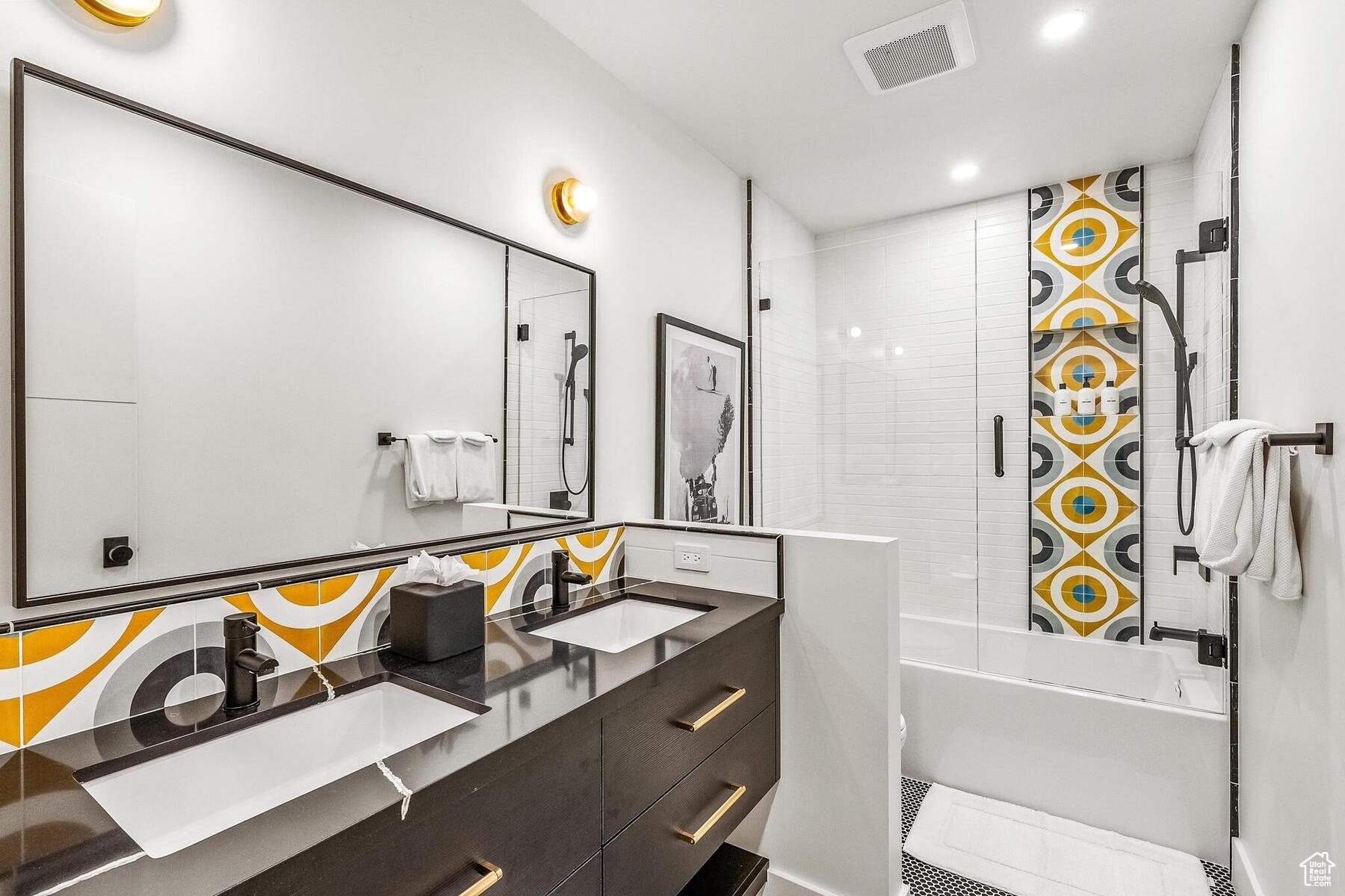 Bathroom featuring tile flooring, dual vanity, and combined bath / shower with glass door