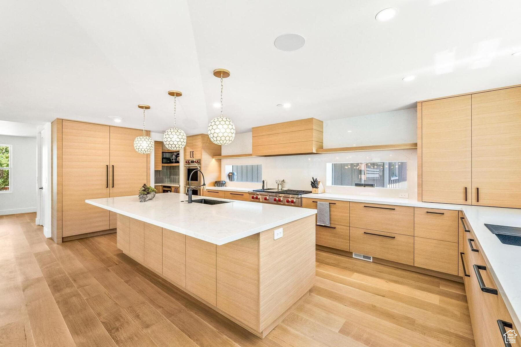 Kitchen featuring light hardwood / wood-style flooring, a kitchen island with sink, sink, light brown cabinetry, and custom exhaust hood