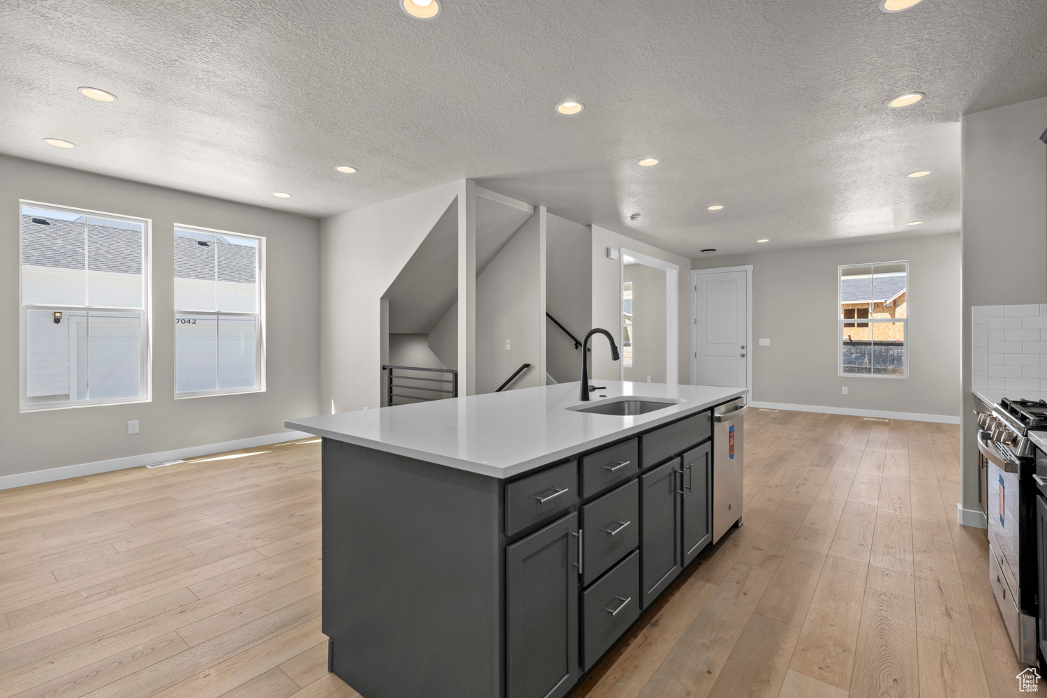 Kitchen with an island with sink, sink, light hardwood / wood-style floors, and stainless steel appliances