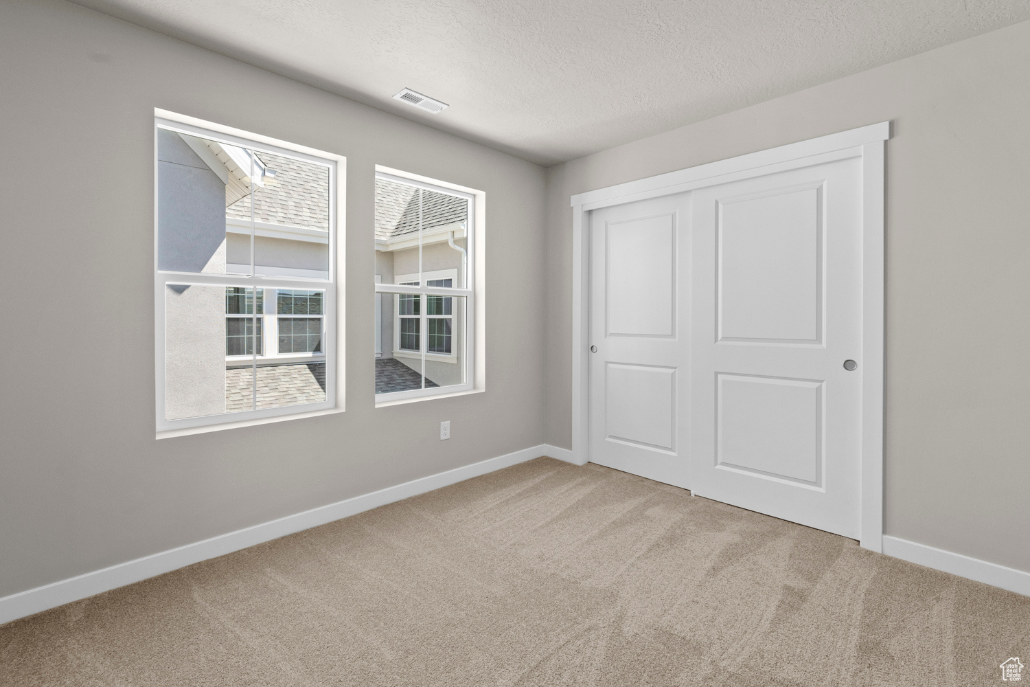 Unfurnished bedroom featuring a textured ceiling, carpet flooring, and a closet