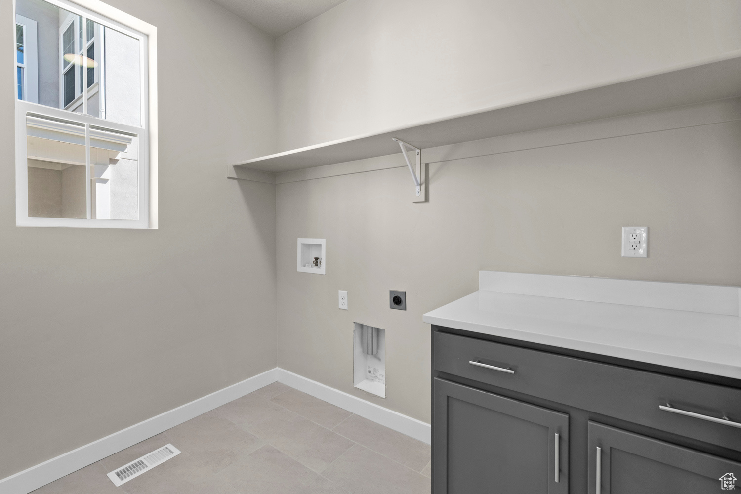 Clothes washing area with electric dryer hookup, washer hookup, light tile flooring, and cabinets